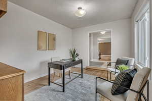 Home office featuring light wood-type flooring and a textured ceiling