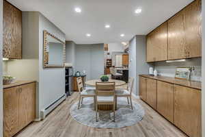 Dining space with a baseboard heating unit, recessed lighting, and light wood finished floors