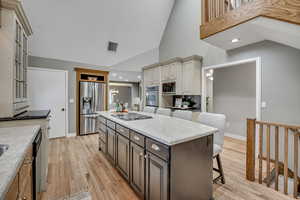 Two tone kitchen featuring dual tone cabinets, lofted ceiling, a breakfast bar, light wood-type flooring, and a center island