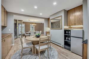 Dining room featuring light wood-type flooring, baseboard heating, and a chandelier