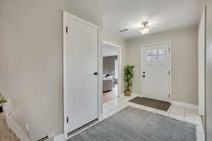 Entryway with a baseboard heating unit and light tile patterned floors