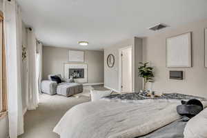 Carpeted bedroom with a fireplace and baseboards