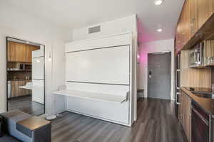 Kitchen featuring modern cabinets, wood finish cabinetry, stainless steel appliances, dark wood-style flooring, and recessed lighting