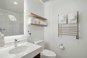 Bathroom with radiator heating unit, vanity, and a towel warming rack