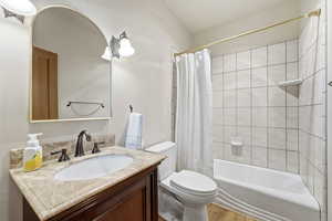 Full bath with shower / bath combo with shower curtain, vanity, and wood finished floors