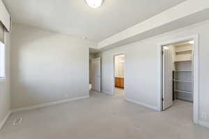 Unfurnished bedroom with light carpet and a walk in closet