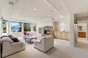 Living room with recessed lighting, a raised ceiling, a fireplace, light colored carpet, and a mountain view