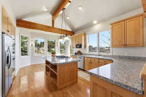 Kitchen with light stone counters, a center island, light wood finished floors, open shelves, and pendant lighting