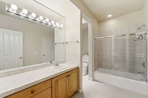 Bathroom featuring vanity and bath / shower combo with glass door
