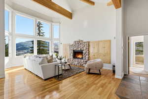 Living room with a mountain view, a stone fireplace, light wood-style flooring, and vaulted ceiling