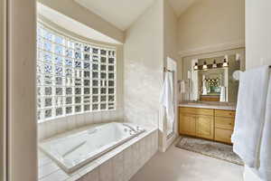 Bathroom featuring vanity, a whirlpool tub, a shower stall, light colored carpet, and lofted ceiling