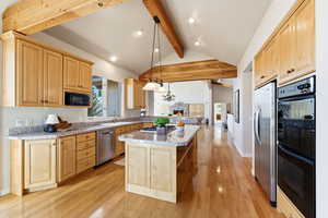 Kitchen with stainless steel appliances, pendant lighting, light wood finish cabinets, and light wood finished floors