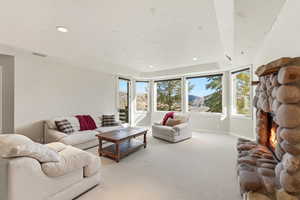 Living room with carpet, a fireplace, recessed lighting, a raised ceiling, and a mountain view