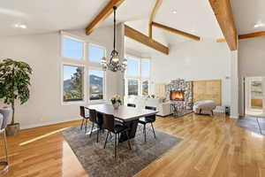 Dining area featuring a fireplace, light wood-style floors, a mountain view, lofted ceiling, and hanging lights