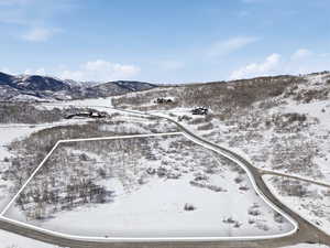 Snowy aerial view with property parcel outlined and a mountain view