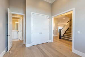Entrance foyer with light wood-style flooring, crown molding, and hanging lights