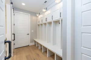Mudroom featuring light wood-style floors, recessed lighting, and a barn door
