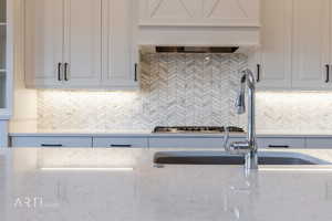 Kitchen with light stone countertops, white cabinetry, and decorative backsplash