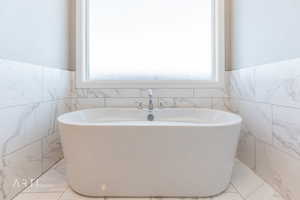 Bathroom featuring a freestanding tub, tile walls, and a wainscoted wall