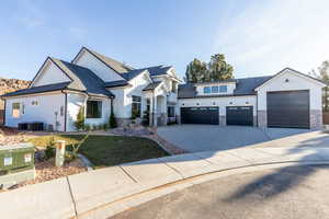 Modern farmhouse style home featuring driveway, board and batten siding, a front lawn, stone siding, and a garage