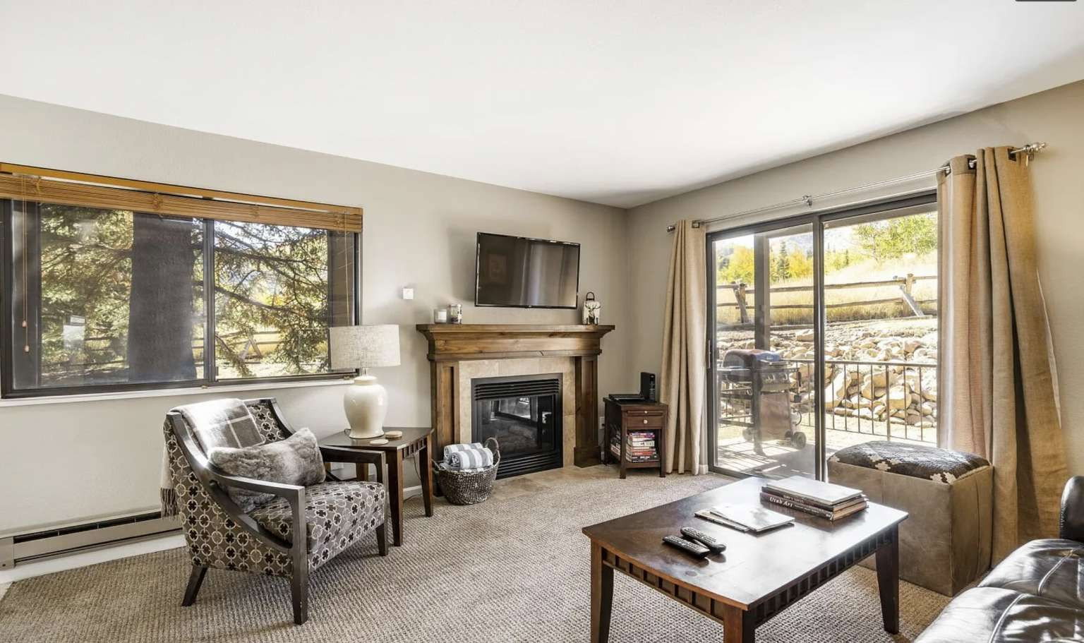Carpeted living area featuring a baseboard heating unit and a tiled fireplace