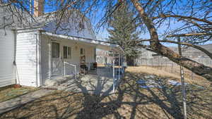 Back of property with a fenced backyard, a chimney, and a patio