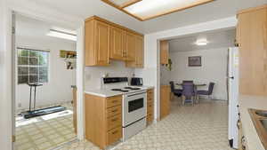 Kitchen with light flooring, white appliances, light countertops, and light wood finish cabinets