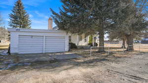 View of front of property featuring a chimney, driveway, and a garage