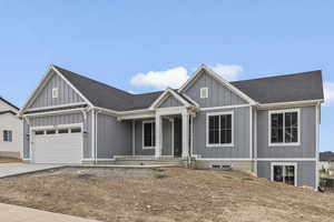 Modern farmhouse featuring a shingled roof, driveway, a porch, and board and batten siding
