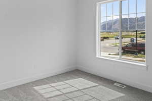 Carpeted spare room featuring a mountain view and baseboards