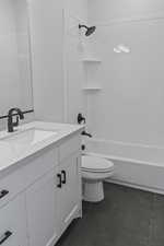 Full bathroom with shower / washtub combination, vanity, and dark tile patterned flooring
