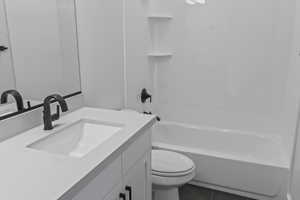 Full bathroom featuring vanity, bathtub / shower combination, and dark tile patterned floors