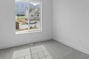 Carpeted empty room with a mountain view and baseboards