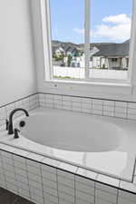 Full bath with a garden tub and a residential view