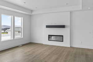 Unfurnished living room featuring a glass covered fireplace and light wood finished floors