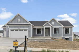 View of front of property with roof with shingles, a porch, driveway, an attached garage, and board and batten siding