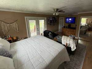 Bedroom with wood finished floors, french doors, crown molding, access to outside, and a ceiling fan