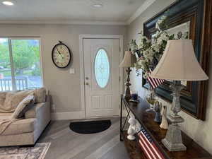 Entryway with dark wood-style floors, a textured ceiling, healthy amount of natural light, ornamental molding, and recessed lighting