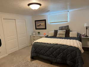 Bedroom with a closet, a textured ceiling, carpet, and crown molding