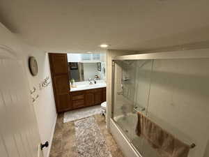 Full bathroom featuring vanity, shower / bath combination with glass door, a textured ceiling, and recessed lighting