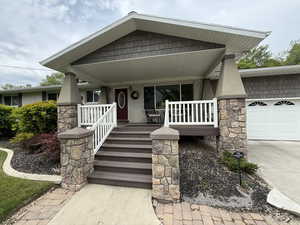 Entrance to property featuring covered porch, an attached garage, and driveway