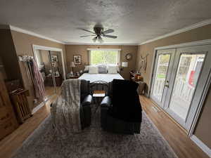Bedroom with a textured ceiling, access to exterior, french doors, crown molding, and a ceiling fan