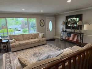 Living area with wood finished floors, a textured ceiling, recessed lighting, and ornamental molding