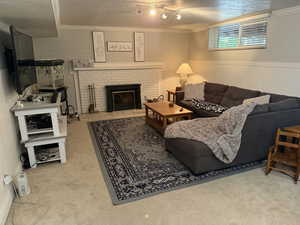 Living room featuring ornamental molding, a textured ceiling, a fireplace, a wainscoted wall, and light colored carpet