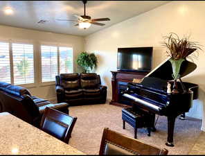 Living room featuring ceiling fan, light carpet, and vaulted ceiling