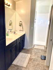Full bathroom with double vanity and baseboards