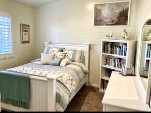 Bedroom with dark colored carpet and baseboards