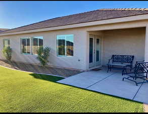 Rear view of property featuring stucco siding, a patio, a yard, and a tiled roof