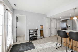 Kitchen with hanging light fixtures, stainless steel refrigerator with ice dispenser, a breakfast bar area, arched walkways, and light tile patterned floors