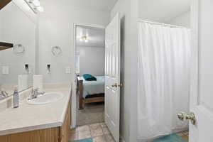 Ensuite bathroom featuring vanity, a textured ceiling, a shower with shower curtain, and light colored carpet